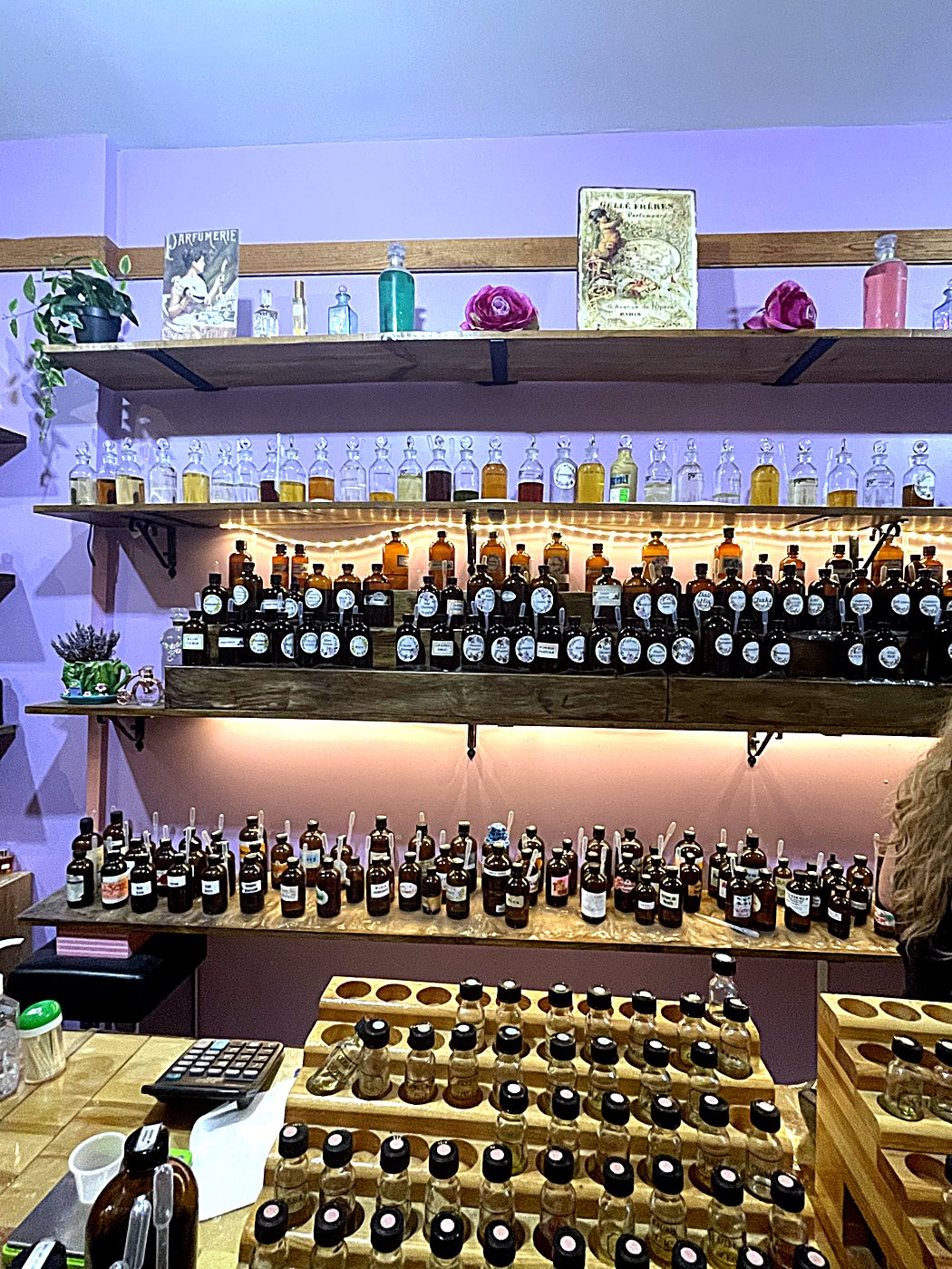 Wooden shelves lined with vintage perfume bottles, amber oils and fairy lights