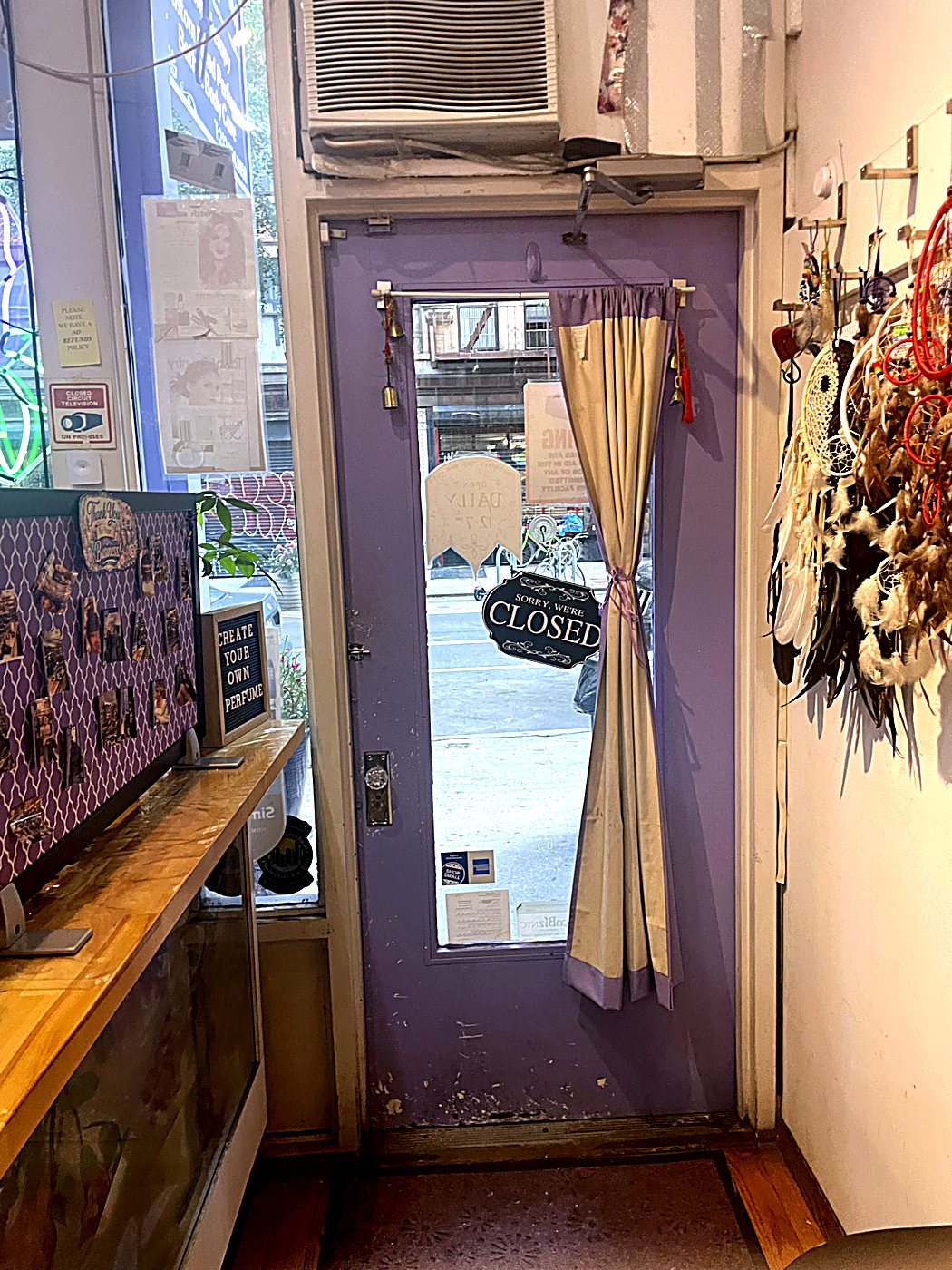 The shop's lavender front door with a cream curtain and a hand-painted closed sign
